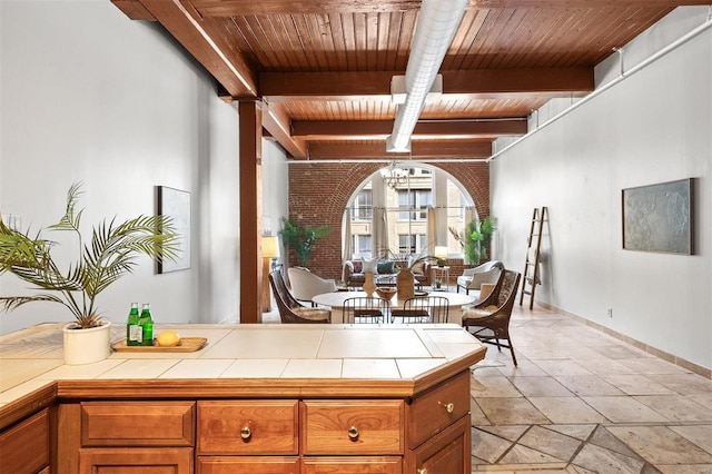 interior space featuring beam ceiling, tile counters, wooden ceiling, and a notable chandelier