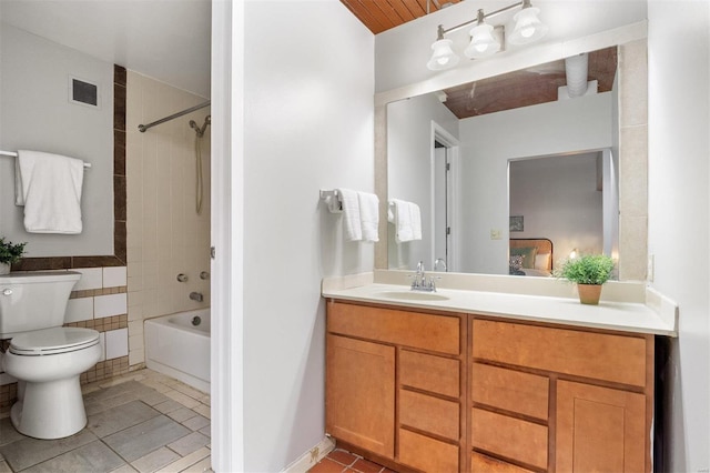 full bathroom with vanity, tiled shower / bath, tile patterned flooring, toilet, and tile walls