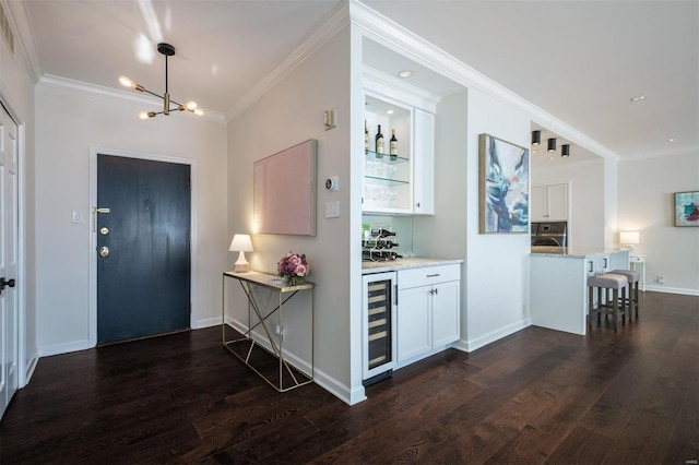 interior space featuring beverage cooler, dark hardwood / wood-style flooring, indoor bar, an inviting chandelier, and crown molding