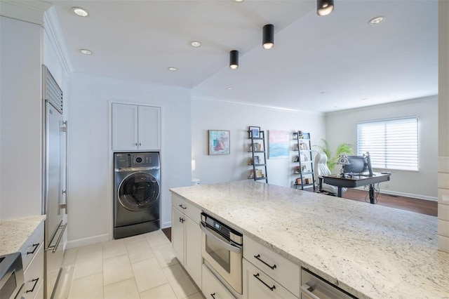 kitchen with light stone countertops, white cabinets, washer / dryer, and appliances with stainless steel finishes