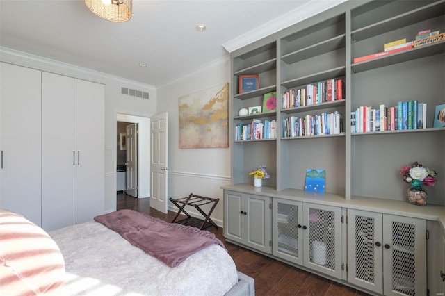 bedroom featuring a closet, dark wood-type flooring, and crown molding