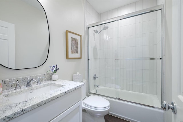 full bathroom featuring enclosed tub / shower combo, vanity, and toilet