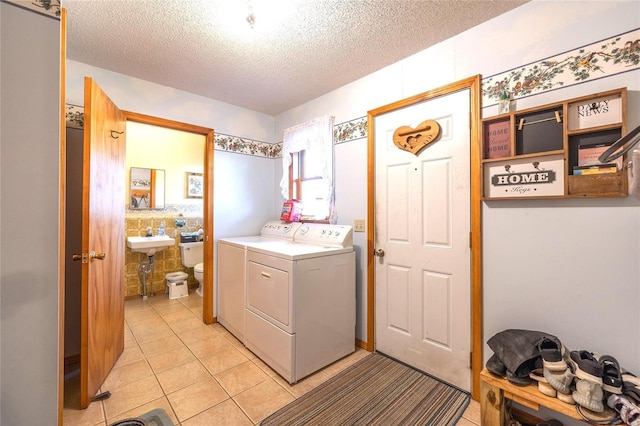 laundry area featuring light tile patterned floors, washer and dryer, and a textured ceiling