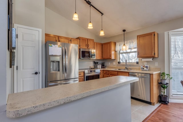 kitchen featuring lofted ceiling, sink, hanging light fixtures, stainless steel appliances, and a wealth of natural light