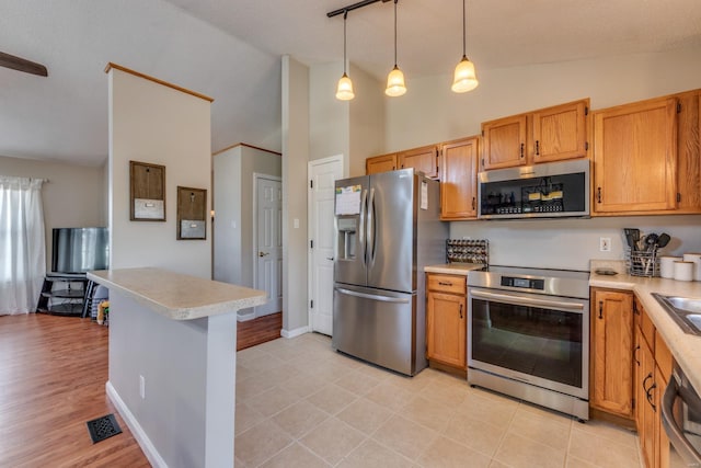 kitchen with sink, decorative light fixtures, high vaulted ceiling, light tile patterned floors, and appliances with stainless steel finishes