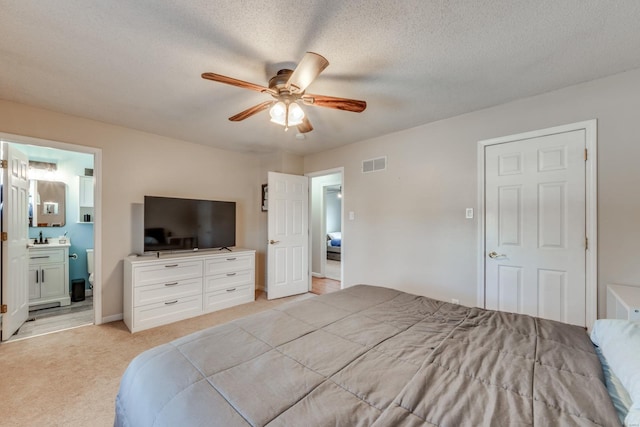 carpeted bedroom featuring sink, ceiling fan, a textured ceiling, and ensuite bathroom