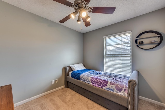 bedroom featuring ceiling fan, light carpet, and a textured ceiling