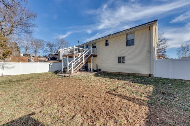 back of house with a deck and a lawn