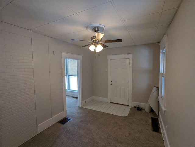 unfurnished room with ceiling fan, a drop ceiling, and light colored carpet