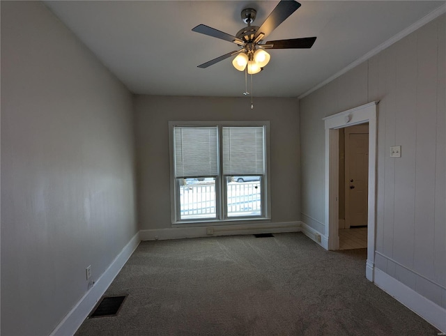 carpeted spare room with ceiling fan and ornamental molding