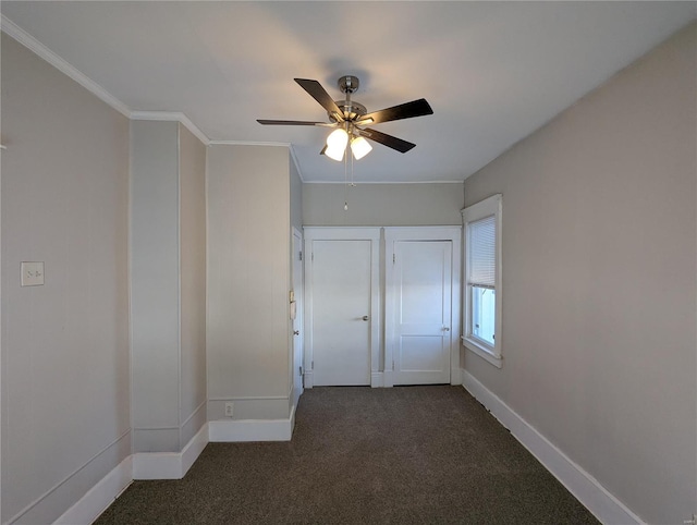 empty room featuring ceiling fan, crown molding, and dark carpet