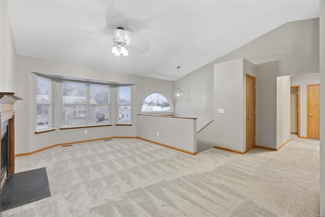 unfurnished living room with ceiling fan, light colored carpet, and vaulted ceiling