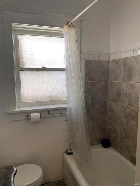 bathroom featuring toilet and shower / bath combo with shower curtain