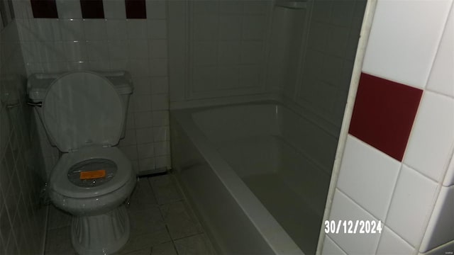 bathroom featuring a tub to relax in, tile patterned flooring, and toilet