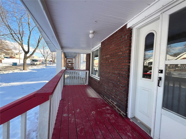 snow covered deck featuring a porch