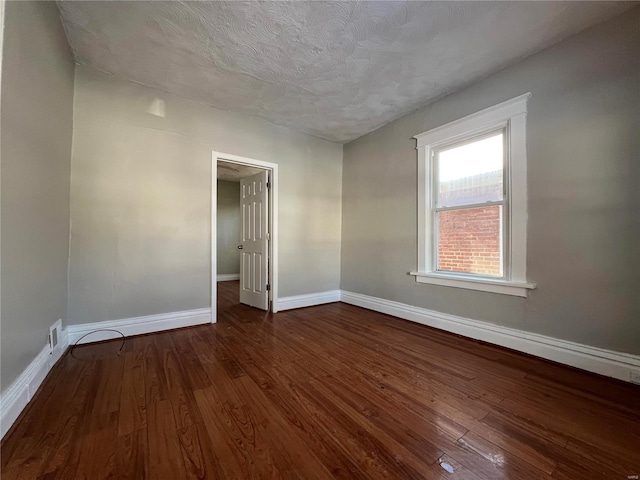 unfurnished room featuring a textured ceiling and dark hardwood / wood-style floors