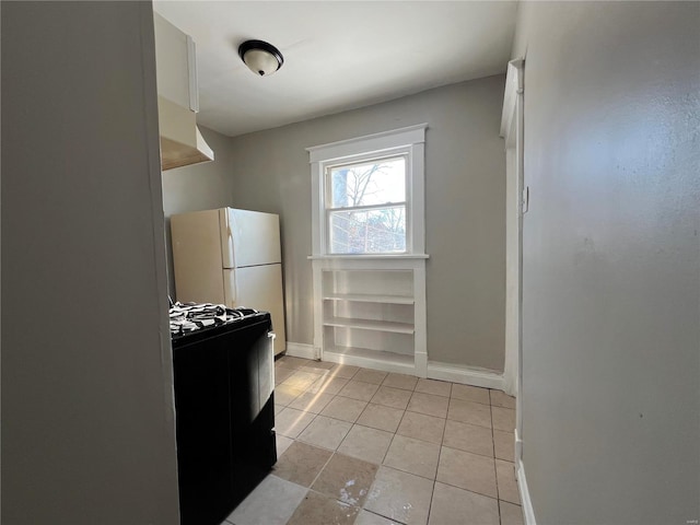 kitchen with white cabinets, gas range, white fridge, and light tile patterned floors