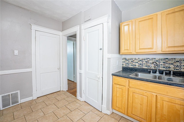 kitchen featuring backsplash, light brown cabinets, light tile patterned floors, and sink