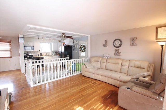 living room with ceiling fan, light wood-type flooring, and sink