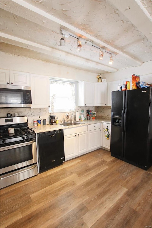 kitchen featuring backsplash, black appliances, white cabinets, sink, and light hardwood / wood-style flooring