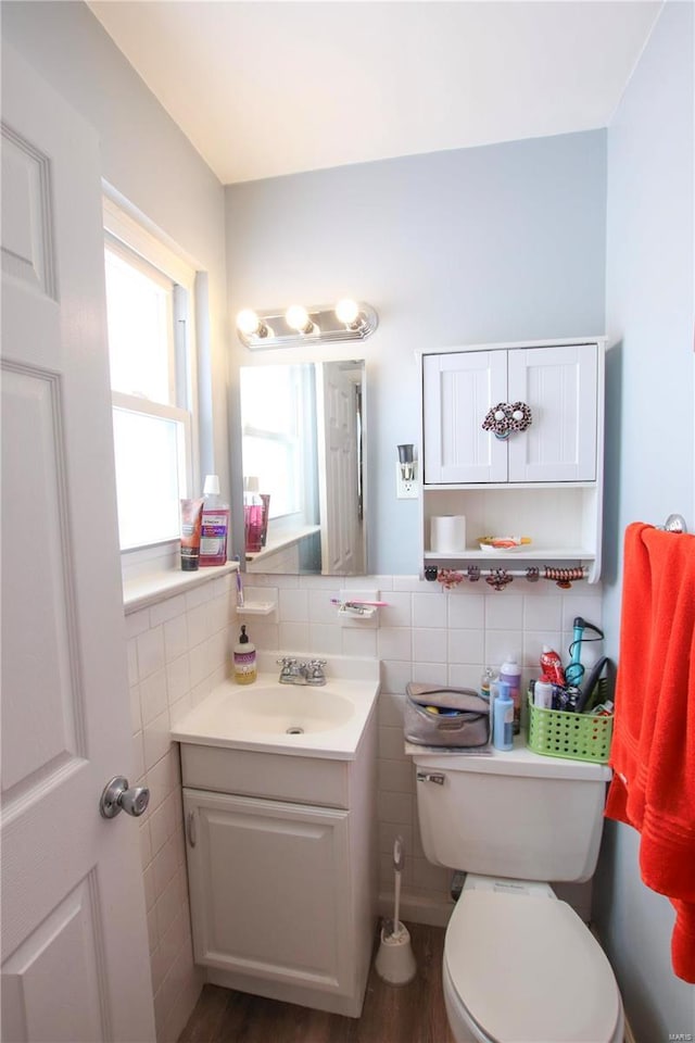 bathroom featuring wood-type flooring, vanity, toilet, and tile walls