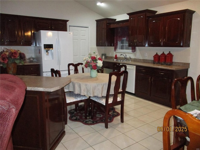 kitchen featuring dark brown cabinets, white appliances, vaulted ceiling, sink, and light tile patterned floors