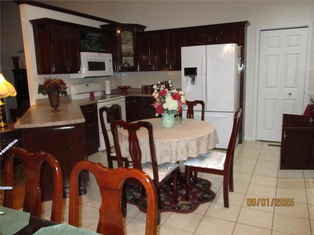 kitchen featuring dark brown cabinets, light tile patterned floors, and white appliances