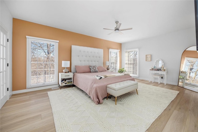 bedroom with ceiling fan, light hardwood / wood-style floors, and multiple windows