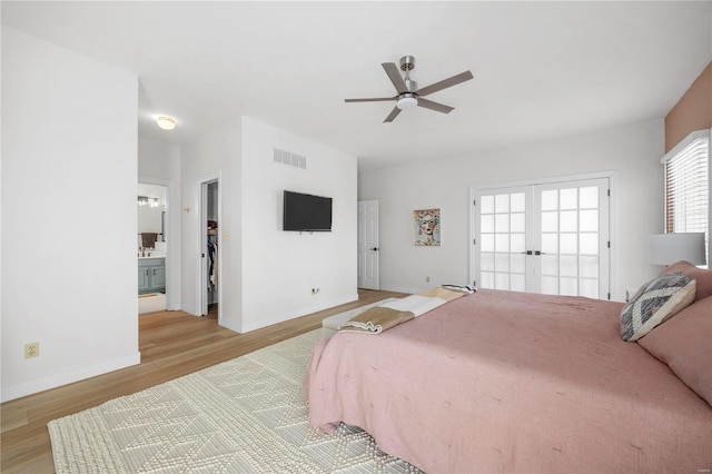 bedroom featuring a spacious closet, french doors, connected bathroom, ceiling fan, and light hardwood / wood-style flooring