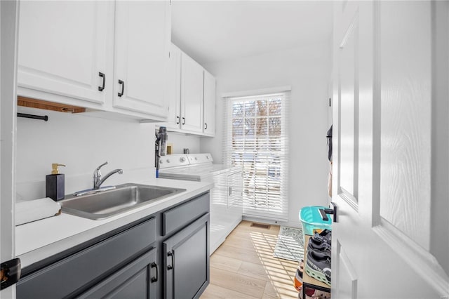 kitchen featuring light hardwood / wood-style flooring, gray cabinets, white cabinetry, separate washer and dryer, and sink