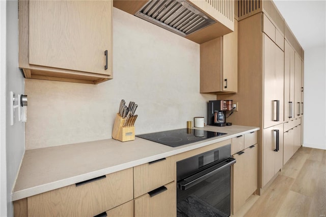 kitchen featuring black appliances, light hardwood / wood-style floors, and light brown cabinetry