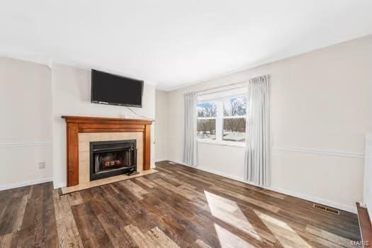 unfurnished living room with wood finished floors, a fireplace with flush hearth, and visible vents