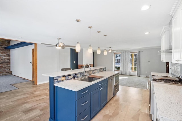 kitchen featuring sink, white cabinetry, blue cabinetry, a center island with sink, and pendant lighting