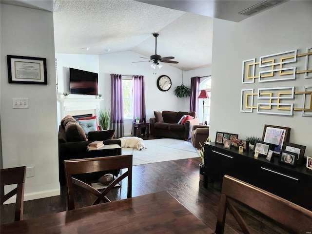 living room with a healthy amount of sunlight, dark hardwood / wood-style flooring, lofted ceiling, and ceiling fan