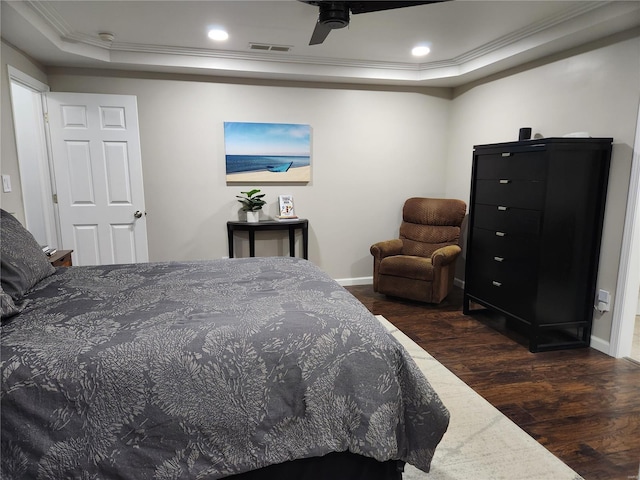 bedroom featuring dark hardwood / wood-style floors, ceiling fan, ornamental molding, and a raised ceiling