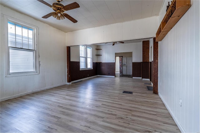 spare room featuring ceiling fan, wooden walls, and light hardwood / wood-style flooring