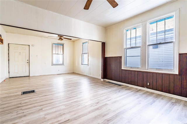 interior space featuring ceiling fan, wooden walls, and light hardwood / wood-style flooring