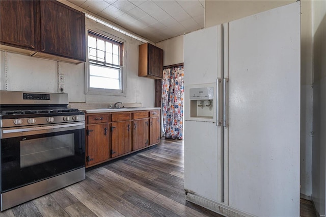 kitchen with dark wood-type flooring, white refrigerator with ice dispenser, sink, and stainless steel range with gas stovetop