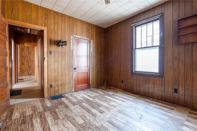 unfurnished room with wood walls and light hardwood / wood-style flooring