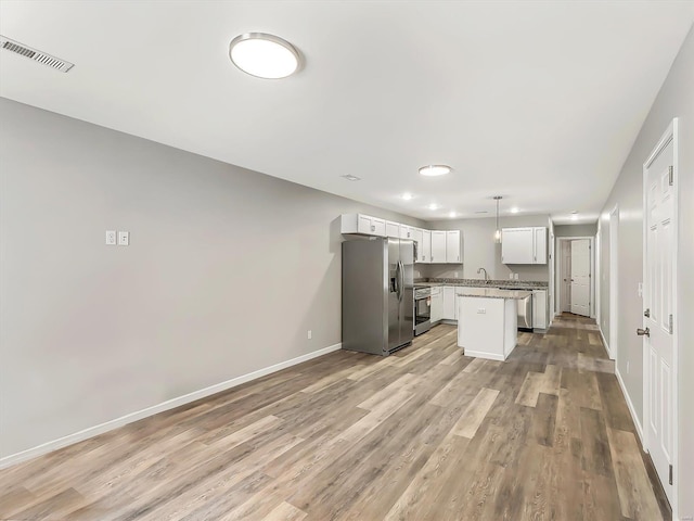 kitchen featuring pendant lighting, light hardwood / wood-style floors, a kitchen island, white cabinetry, and stainless steel appliances