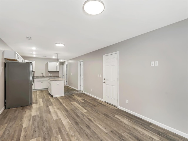 kitchen with stainless steel fridge, sink, decorative light fixtures, white cabinets, and a center island