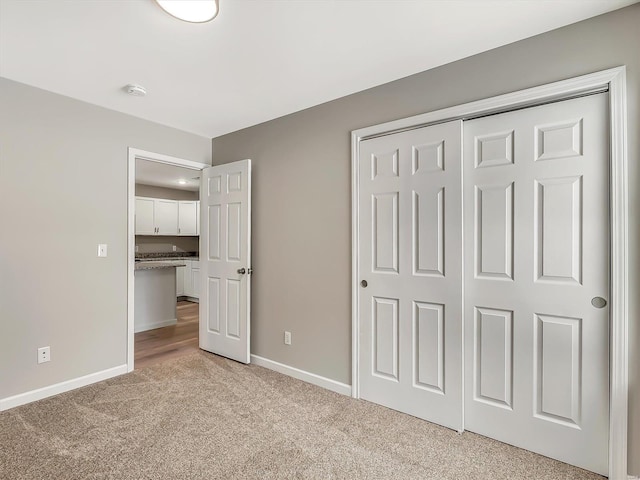 unfurnished bedroom with light carpet and a closet