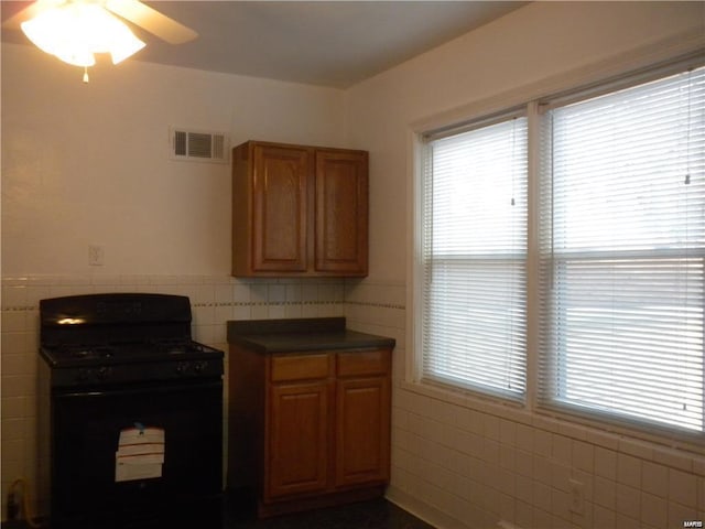 kitchen featuring tile walls, ceiling fan, and black gas stove