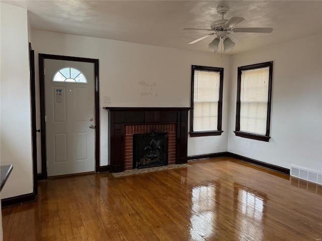 unfurnished living room featuring hardwood / wood-style flooring, a fireplace, and ceiling fan