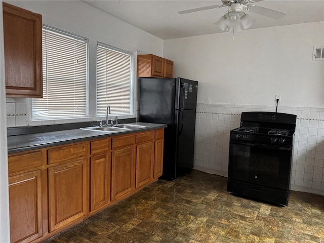 kitchen featuring ceiling fan, sink, tile walls, and black appliances