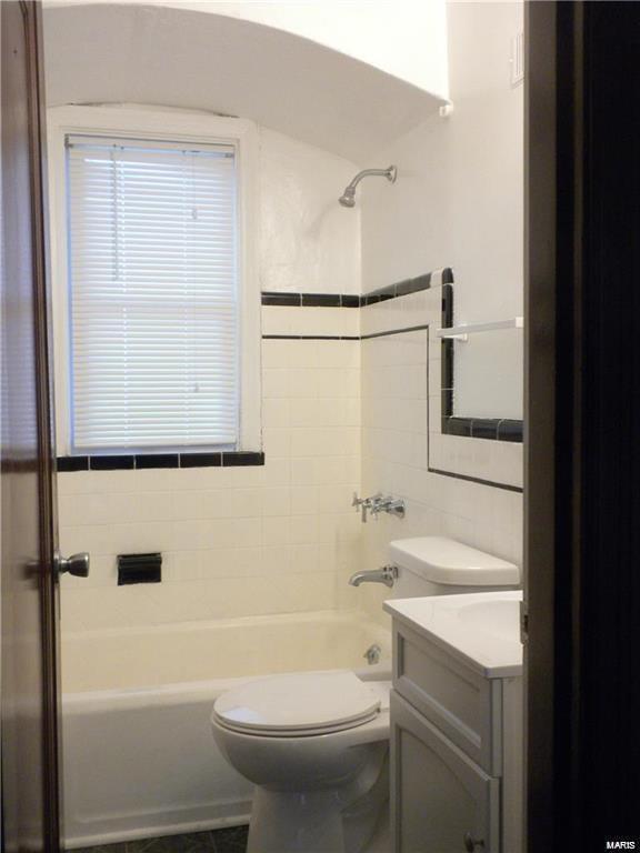 full bathroom featuring vanity, toilet, tile walls, and tiled shower / bath