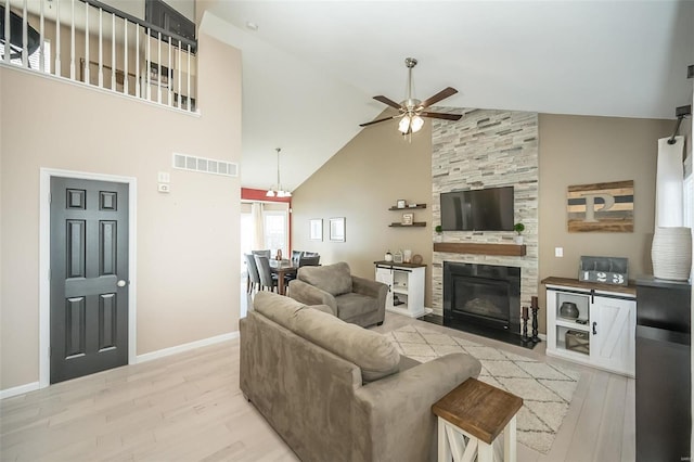 living room with a tiled fireplace, ceiling fan, high vaulted ceiling, and light hardwood / wood-style floors