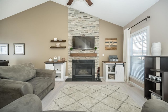 living room with lofted ceiling, light hardwood / wood-style floors, a large fireplace, and ceiling fan