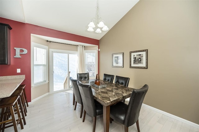 dining space featuring lofted ceiling, a notable chandelier, and light hardwood / wood-style flooring