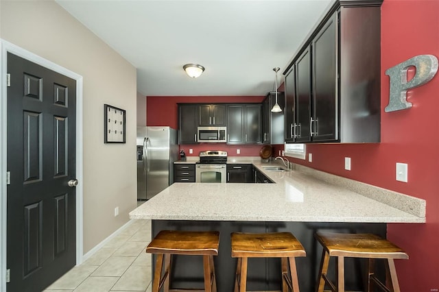 kitchen featuring a breakfast bar, pendant lighting, light tile patterned floors, kitchen peninsula, and stainless steel appliances